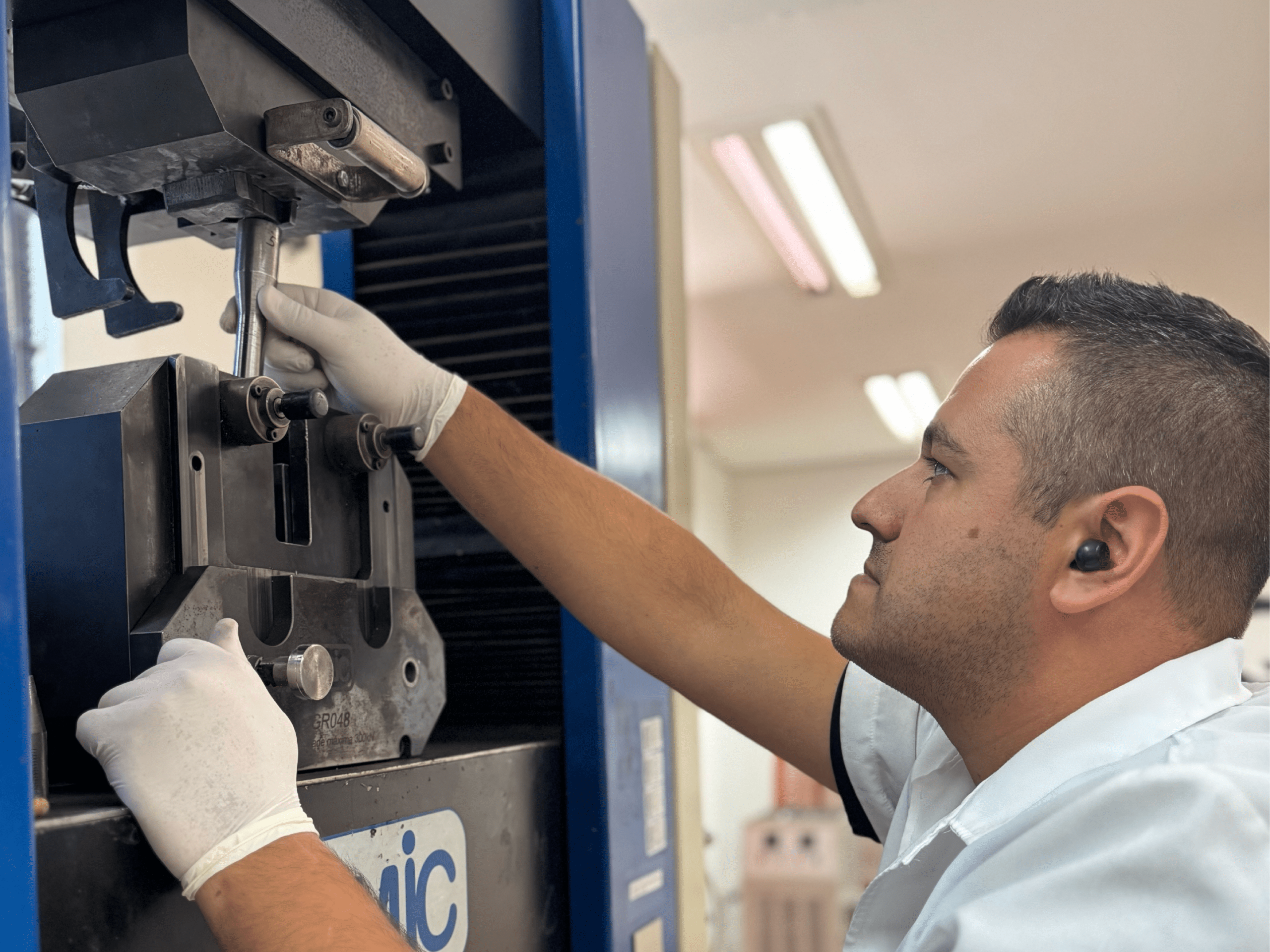 técnico inserindo corpo de prova em equipamento de ensaio de tração