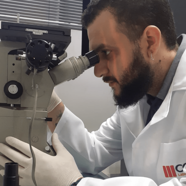 imagem ilustra um laboratorio acreditado, apresenta um técnico analisando um material em um microscópio